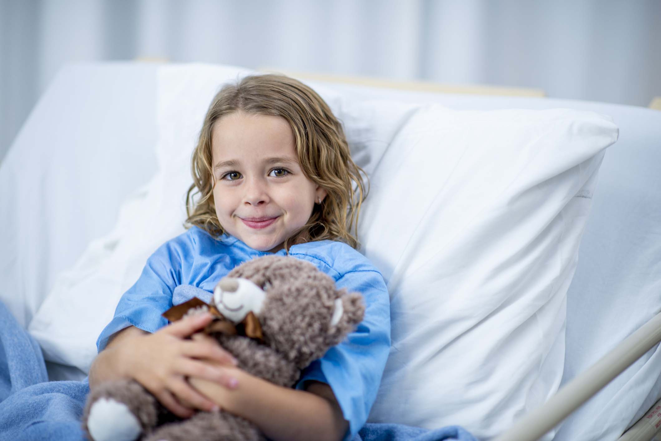 child in hospital bed smiling